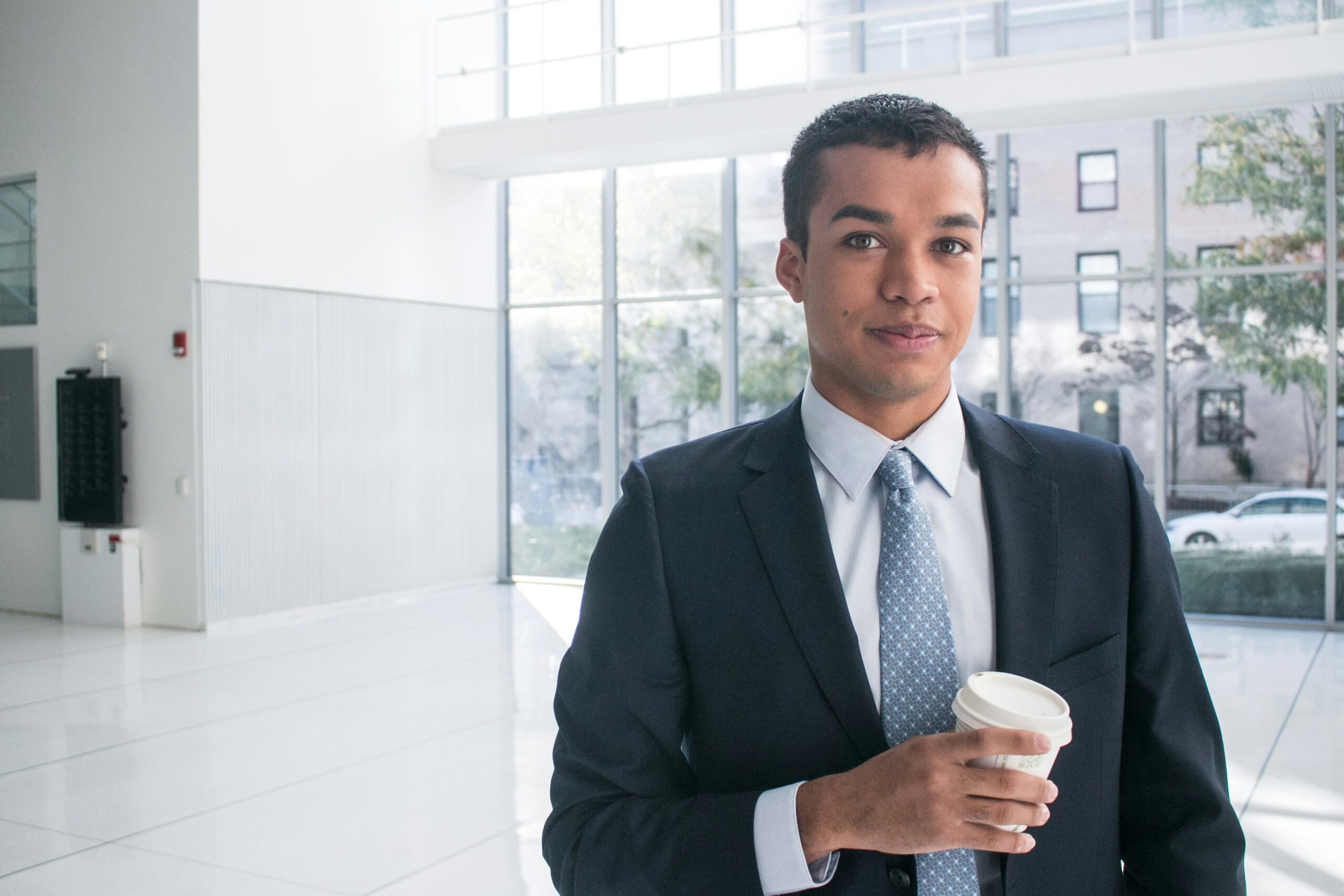 A sales professional holding a coffee cup in an office lobby